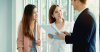 Three people in a room looking over a piece of paper and discussing it. One man is in a suit next to two ladies.